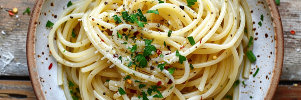 Spaghetti aglio e olio auf rundem Teller, mittig angerichtet mit Öl, Petersilie, Chili und Knoblauch