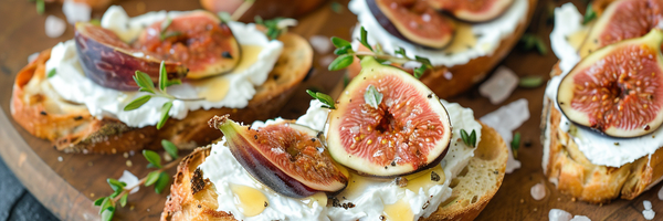 Bruschetta mit Ziegenkäse, Feigen und Honig auf dunklem Teller, zentriert angerichtet